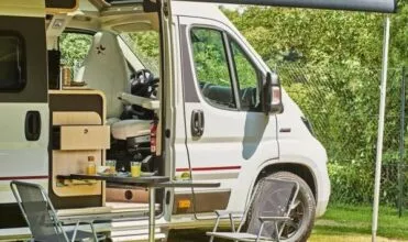 camping-car avec auvent déployé, table et chaises installées