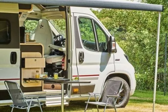 camping-car avec auvent déployé, table et chaises installées